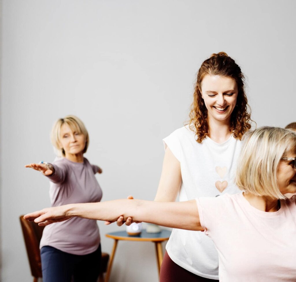 Yoga Lehrerin unterstützt Schülerin für ein besseres Körpergefühl